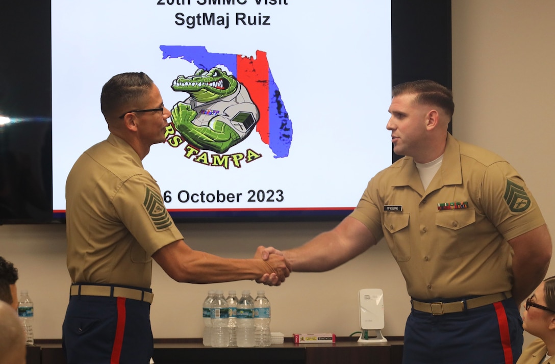 U.S. Marine Corps Sgt. Maj. Carlos Ruiz, Sergeant Major of the Marine Corps, hands a coin to Staff Sgt. Camden Wysong, recruiter with Recruiting Sub Station Port Richey, Tampa, Florida, Oct. 6, 2023. Wysong was identified as a recruiter that performs exceptionally well, even while recruiting in an area that historically does not produce many contracts. (U.S. Marine Corps Photo by Sgt. Erin Morejon)