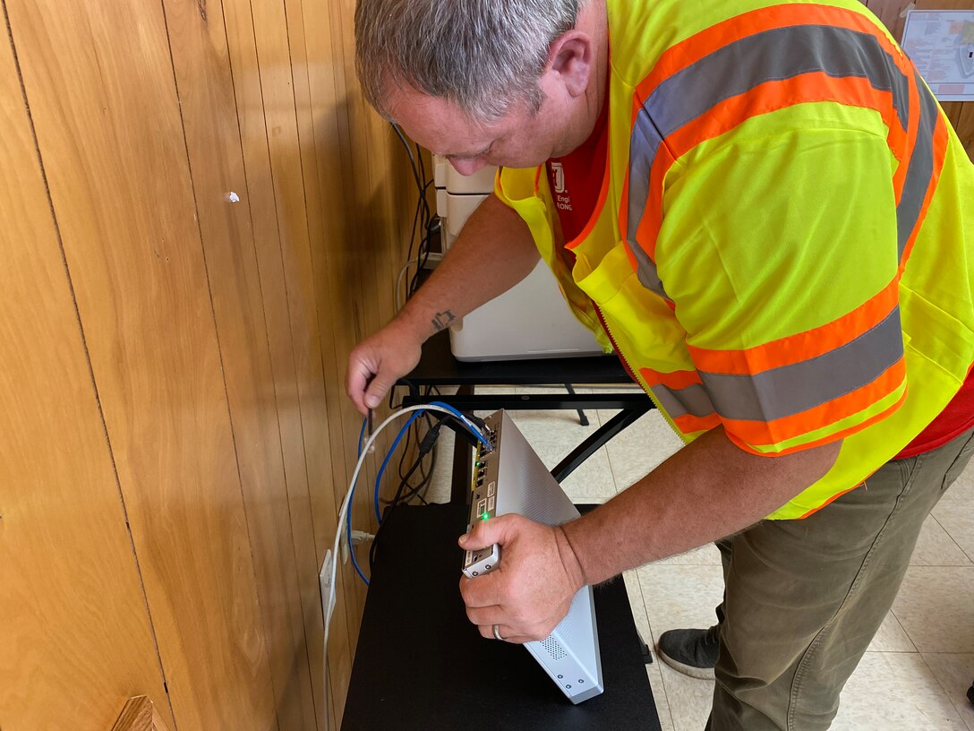 U.S. Army Corps of Engineers CIO/G6 Enterprise Emergency Response Team member Dale Carton installs a Wi-Fi router in a construction trailer at the site where a temporary elementary school is being built.