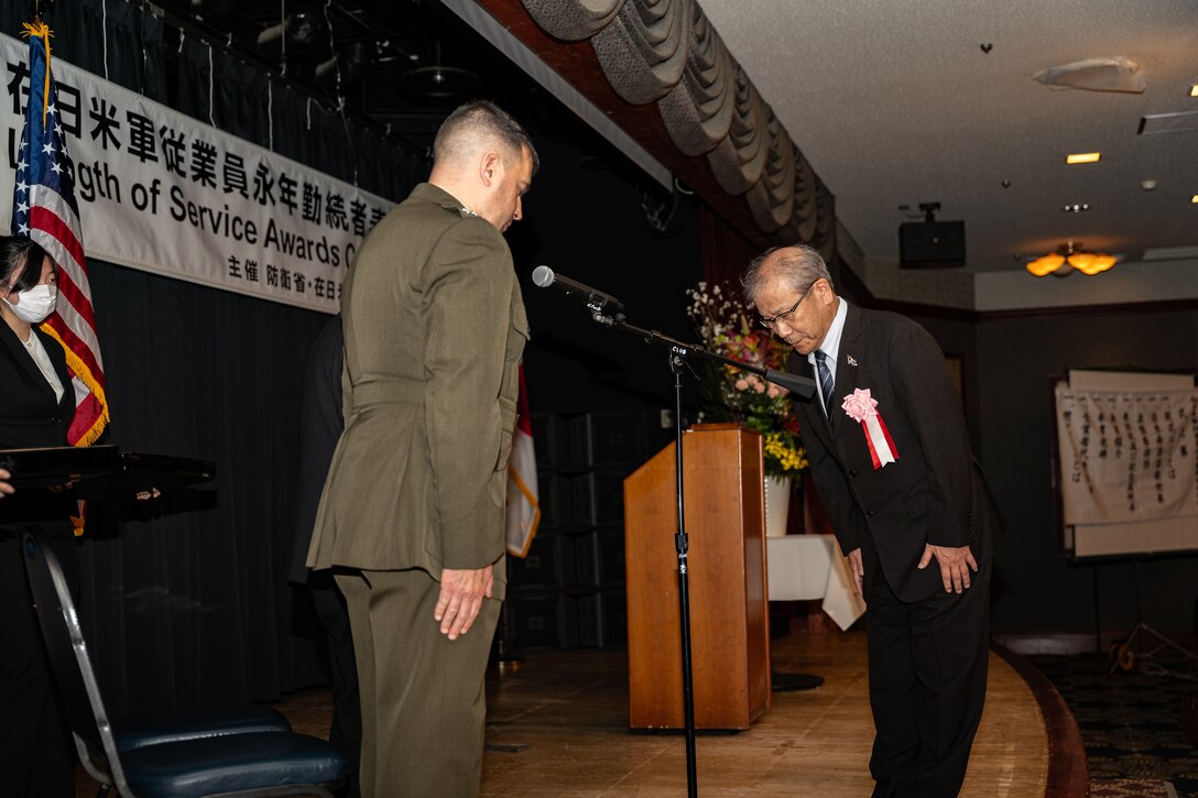 U.S. Marine Corps Col. Richard Rusnok, the commanding officer of Marine Corps Air Station Iwakuni, and Ikeada Takao, the representative for awardees with 40 years of service, bow to each other during an award ceremony at MCAS Iwakuni, Japan, Nov. 15, 2023. The ceremony celebrates Master Labor Contractors years of service to the air station. (U.S. Marine Corps photo by Lance Cpl. Long)