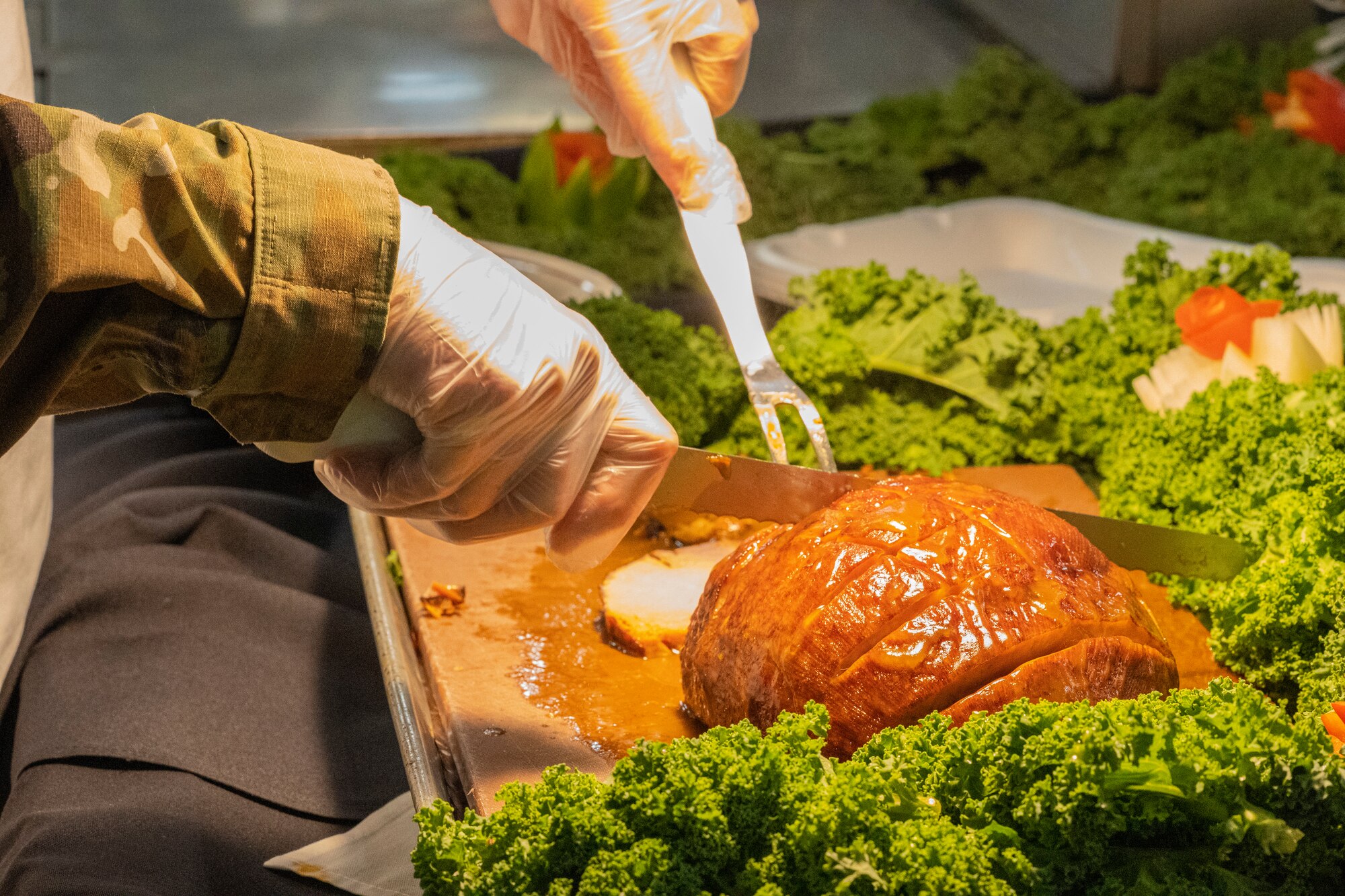 A member of the 81st Training Wing slices baked ham to serve during the Thanksgiving meal at Keesler Air Force Base, Mississippi, Nov. 23, 2023.