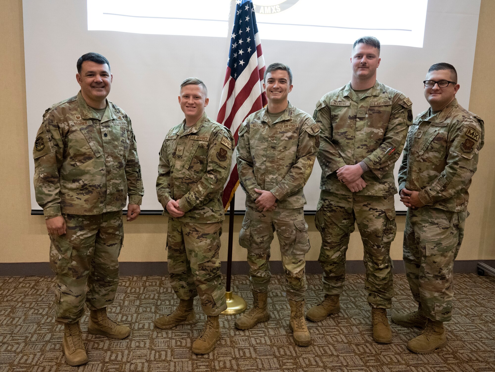 A weapons load team from the 34th and 37th aircraft maintenance units pose with their leadership following a coin ceremony at Ellsworth Air Force Base, South Dakota, Nov. 22, 2023.