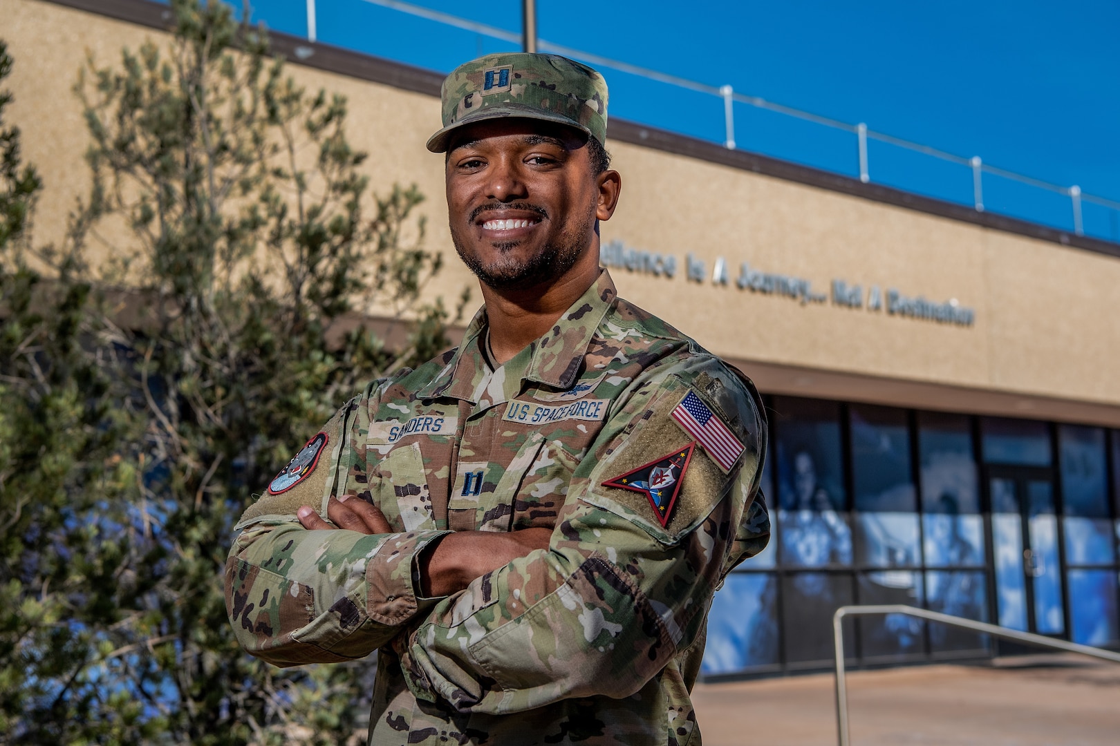 Man in military uniform smiles for a photo with his arms crossed