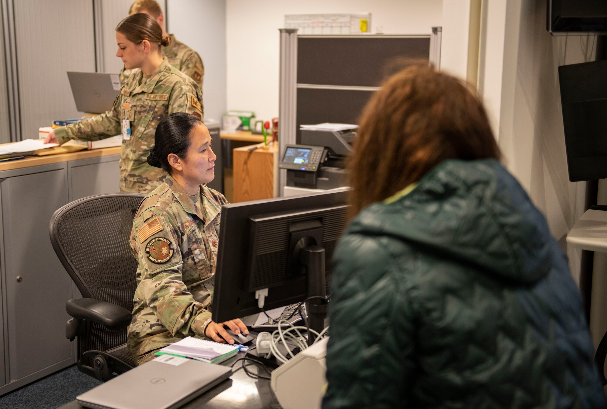 Maj. Rowena Dacumos, 423d Medical Squadron medical operations flight commander, left, checks a patient into the clinic at RAF Alconbury