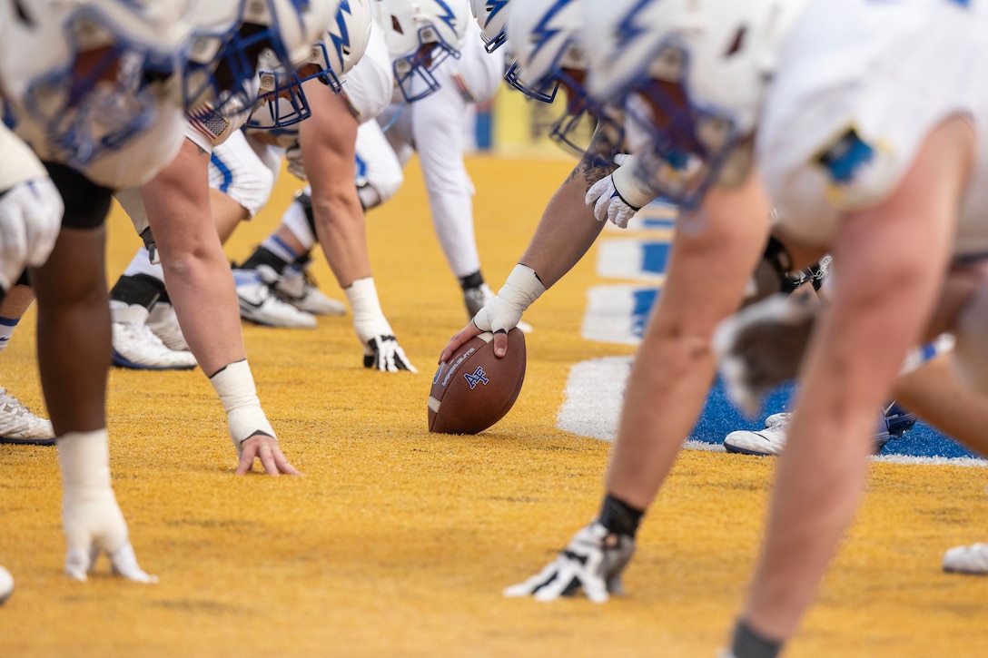 Football players from opposing teams line up in a ready position,