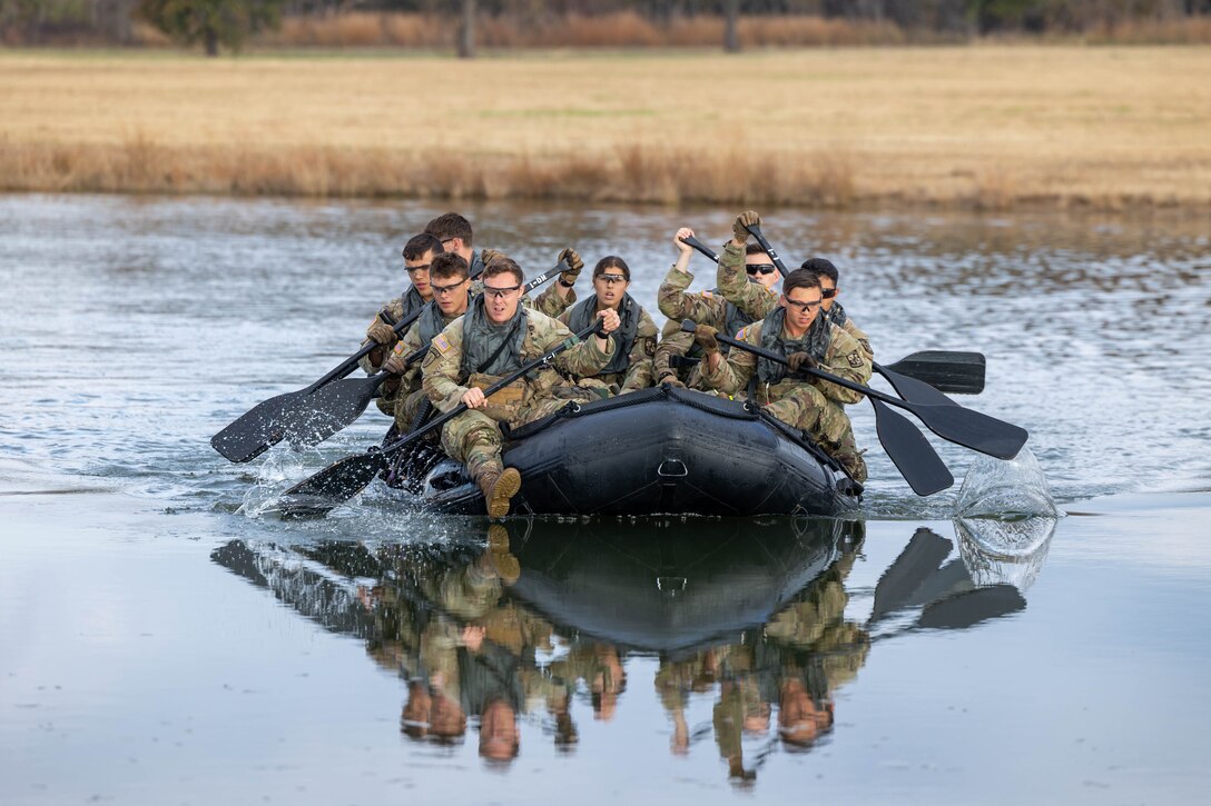 A group of cadets row a rubber raft.