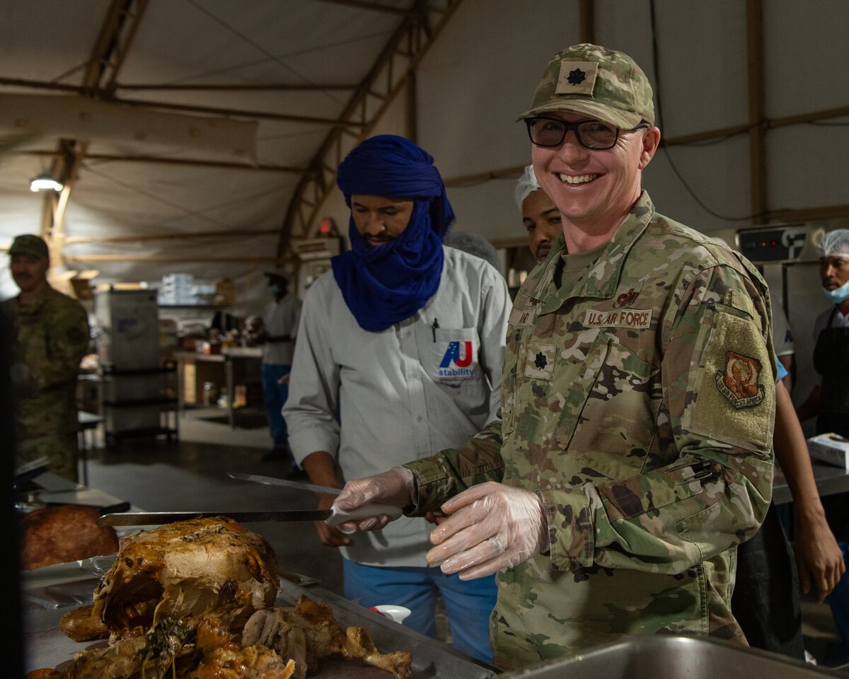 A U.S. Airman serves Thanksgiving food to deployed service members.