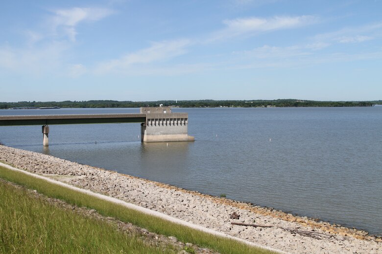 Water can be seen on the right with rocks and grass on the left and blue sky in the background.