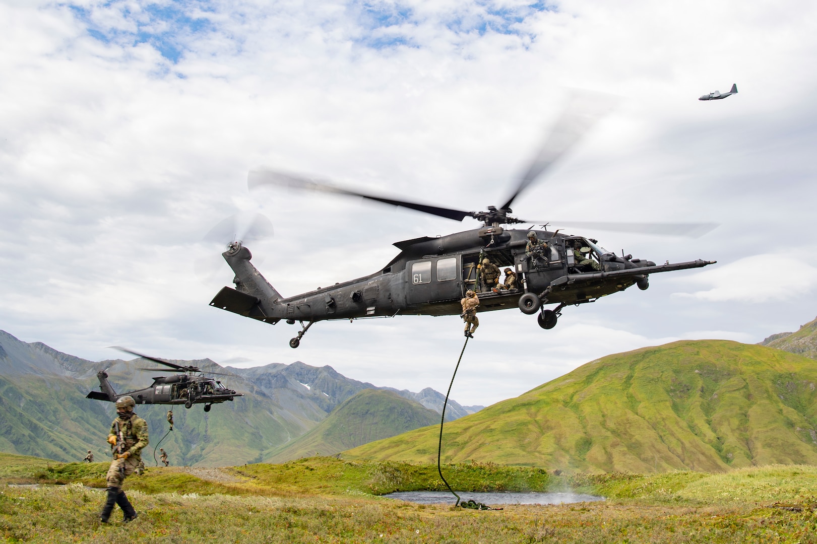 East-Coast-based U.S. Naval Special Warfare Operators (SEALs) fast-rope from U.S. Army MH-60M helicopters, assigned to the 160th Special Operations Aviation Regiment (SOAR), while an AC-130J Ghostrider provides overwatch on Attu Island, Alaska, Aug. 31, 2023, as part of Operation POLAR DAGGER.