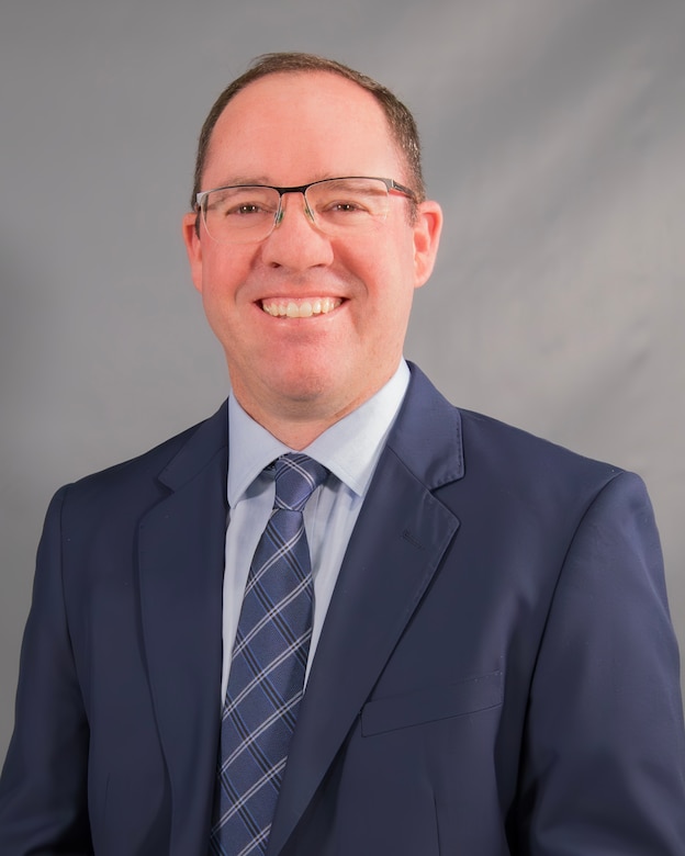 A man in a suit smiles at the camera