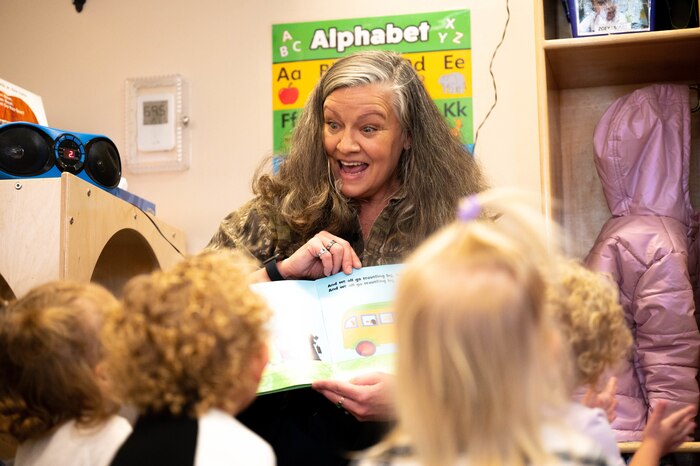 A teacher reads a book to children