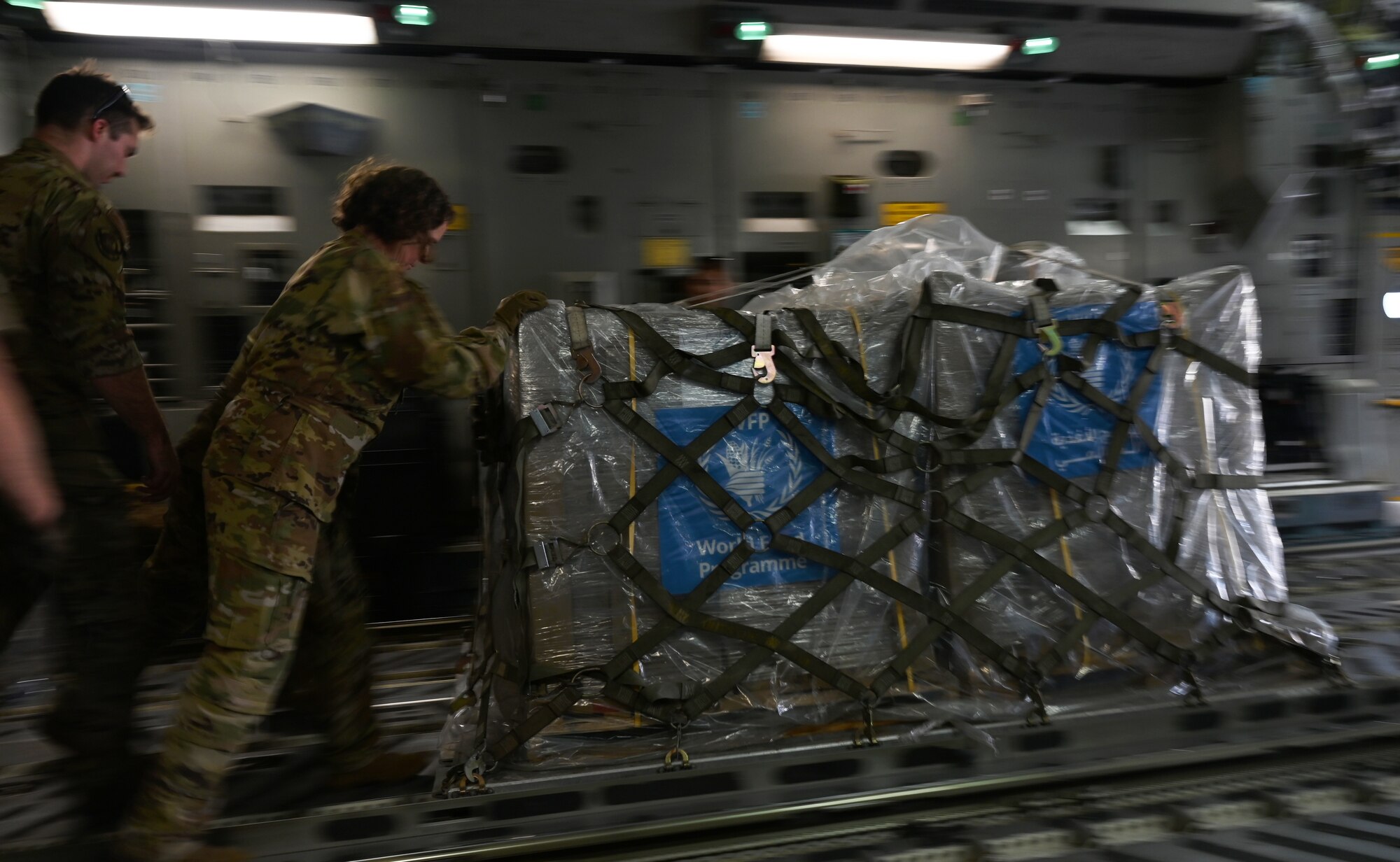 Airmen and U.S. Agency for International Development personnel offload 54,000 pounds of humanitarian aid from a C-17.