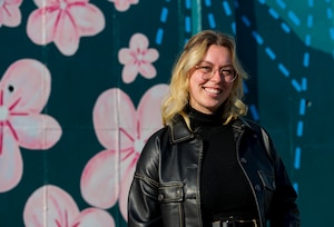 Tenley Brady, spouse of 1st Lt. Tre Brady, 303rd Intelligence Squadron flight commander and lead painter, stands in front of a new mural at Osan Air Base, Republic of Korea, Nov. 28, 2023. Brady led 25 volunteer spouses, dependents and military personnel to complete the mural in an effort to showcase appreciation for Korean culture. (U.S. Air Force photo by Senior Airman Kaitlin Castillo)