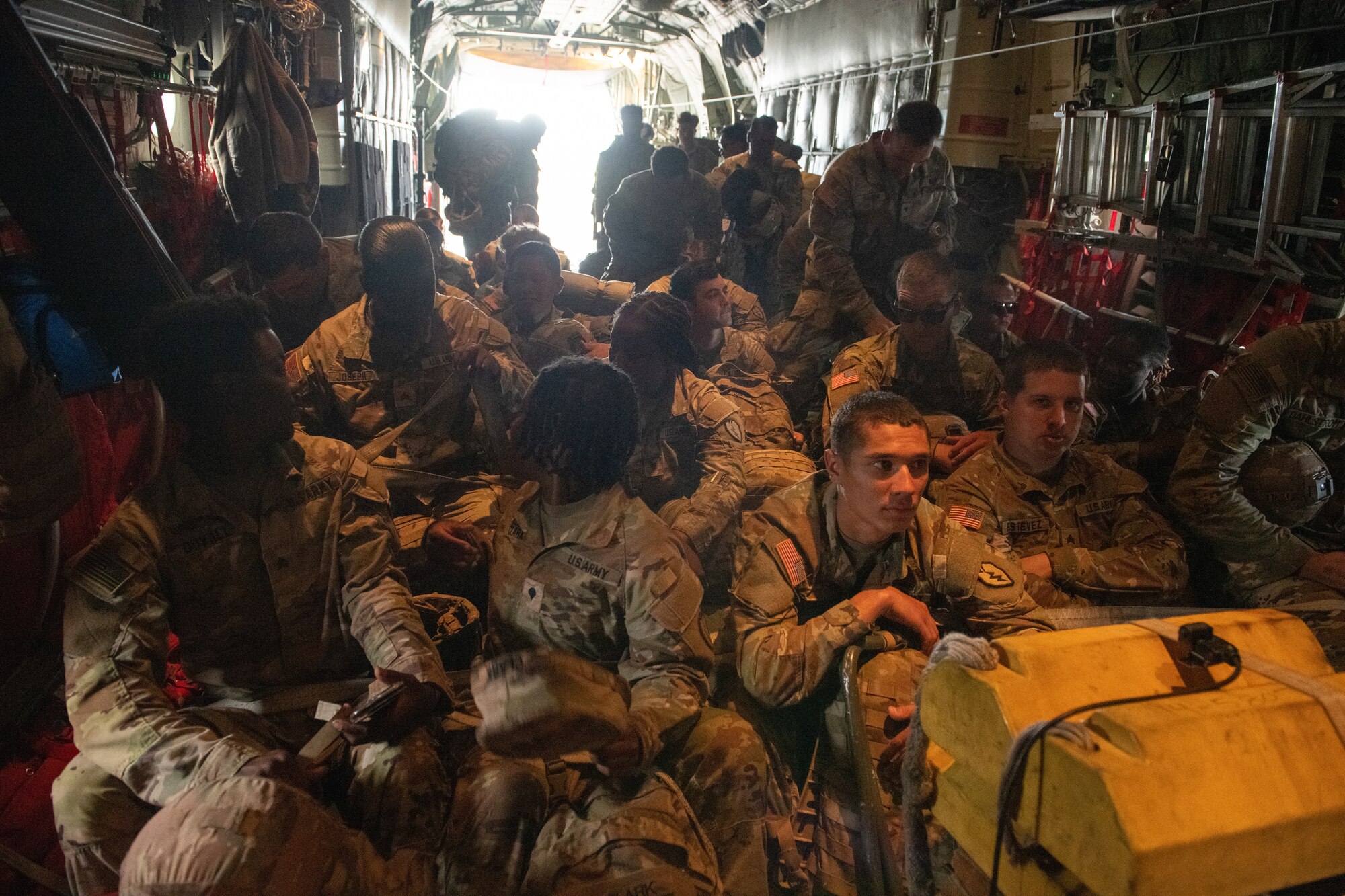Soldiers sit inside of an aircraft.