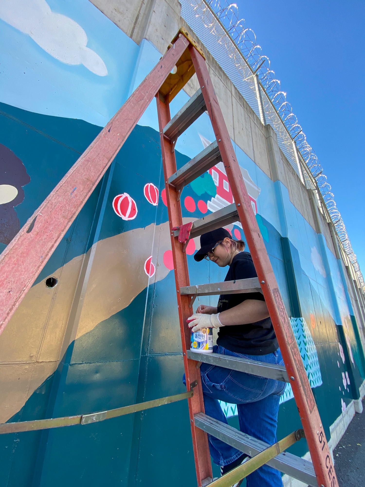 Chloe O’ Brien, military child, helps paint a new mural at Osan Air Base, Republic of Korea, Nov. 13, 2023. Volunteers of all ages came together to invest in the art piece, turning a blank wall into a collaborative effort and a shared goal. (Courtesy photo)