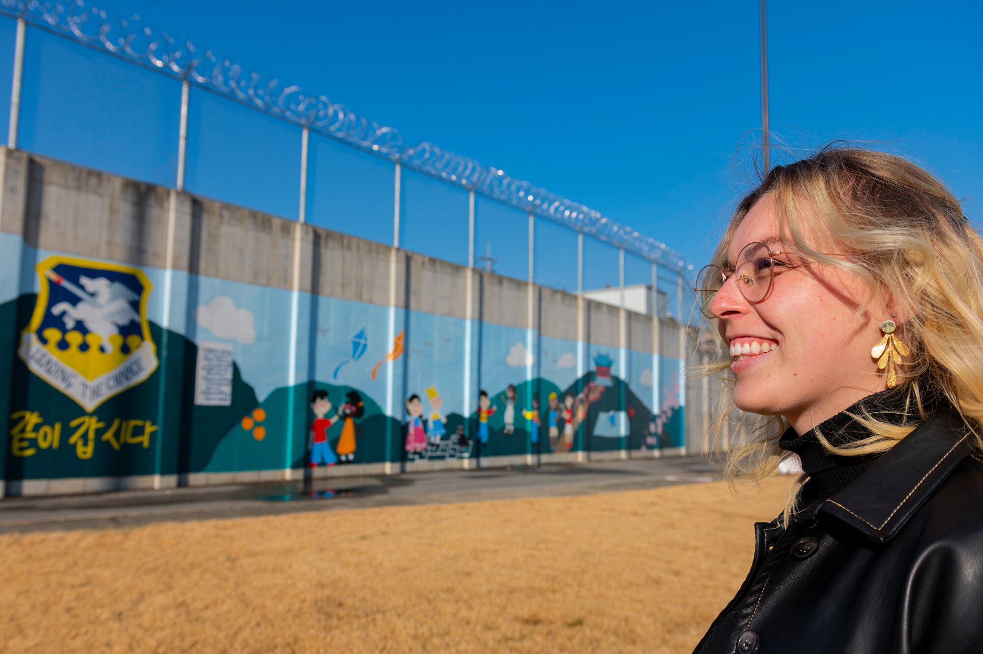 Tenley Brady, spouse of 1st Lt. Tre Brady, 303rd Intelligence Squadron flight commander and lead painter, admires a new mural at Osan Air Base, Republic of Korea, Nov. 28, 2023. Brady brought community personnel together through the base beautification project, showcasing the importance of comradery through creativity. The mural was completed in an effort to showcase appreciation for Korean culture. (U.S. Air Force photo by Senior Airman Kaitlin Castillo)