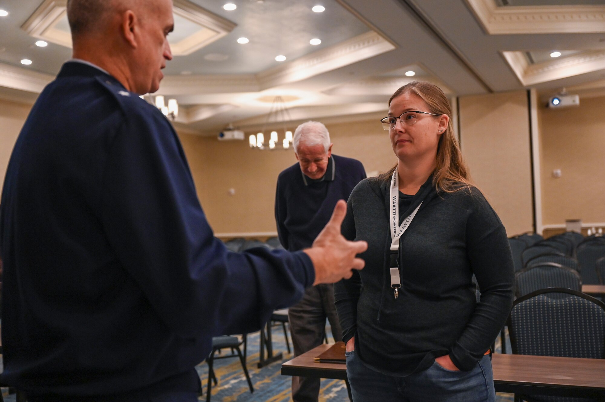 A man and woman talk to each other in a large conference room.