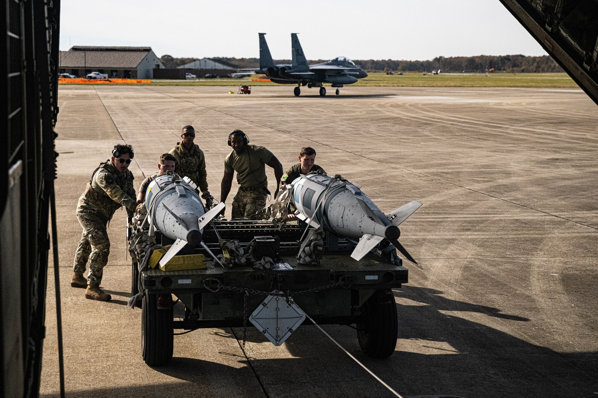 Airmen load fake munitions into the back of a C-130J.
