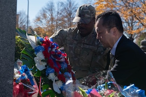 Two people lay a wreath at a memorial monument.
