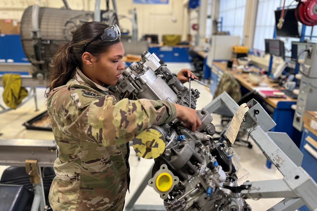 An airman works on an aircraft engine.