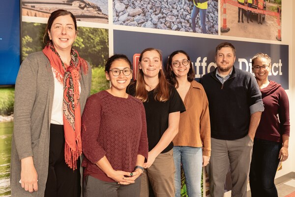 Employees from the U.S. Army Corps of Engineers stand together for a group photo in front of a mural.