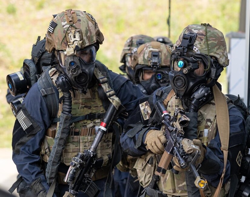 Soldiers stand in formation wearing tactical gear.