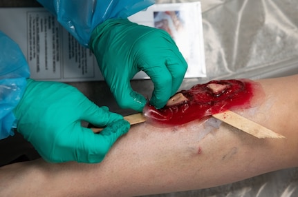 Joint Base Charleston Airmen participate in a medical exercise where they act as patients with simulated wounds. Medical Group staff wear protective hear as they treat the simulated patients.