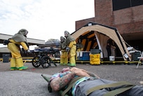 Joint Base Charleston Airmen participate in a medical exercise where they act as patients with simulated wounds. Medical Group staff wear protective hear as they treat the simulated patients.