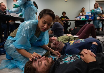 Joint Base Charleston Airmen participate in a medical exercise where they act as patients with simulated wounds. Medical Group staff wear protective hear as they treat the simulated patients.