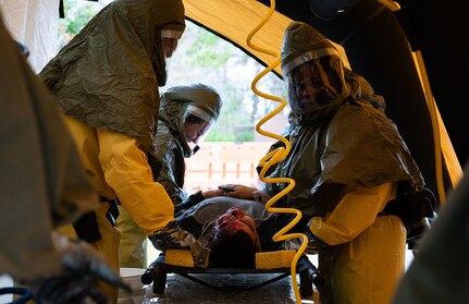 Joint Base Charleston Airmen participate in a medical exercise where they act as patients with simulated wounds. Medical Group staff wear protective hear as they treat the simulated patients.