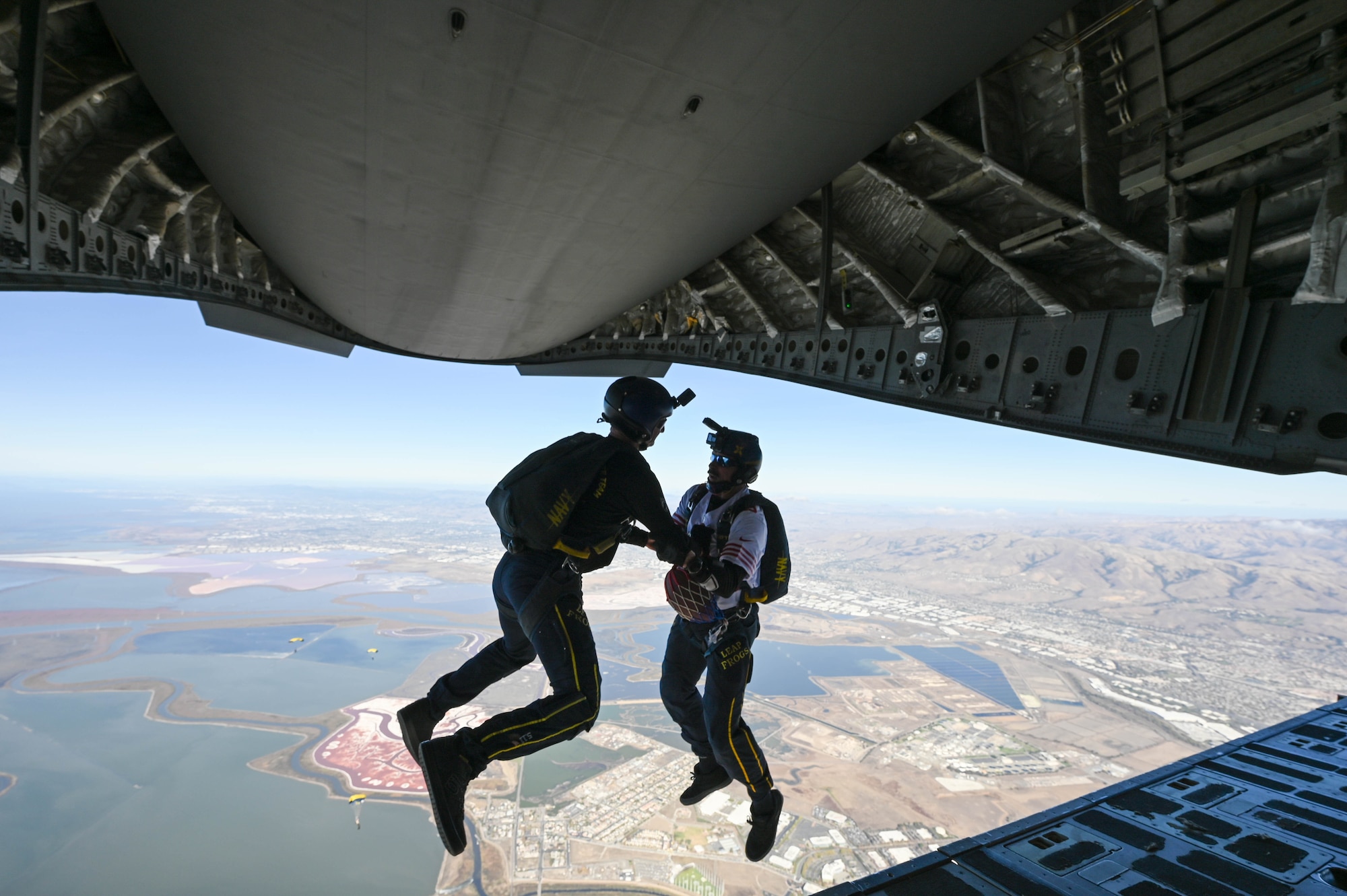 Members of the Navy Parachute Team “The Leap Frogs” exit a C-17 Globemaster III aircraft adove in Santa Clara, California, Nov. 19, 2023. The Leap Frogs are the official parachute demonstration team of the U.S. Navy. (U.S. Air Force photo by Senior Airman Trenton Jancze)