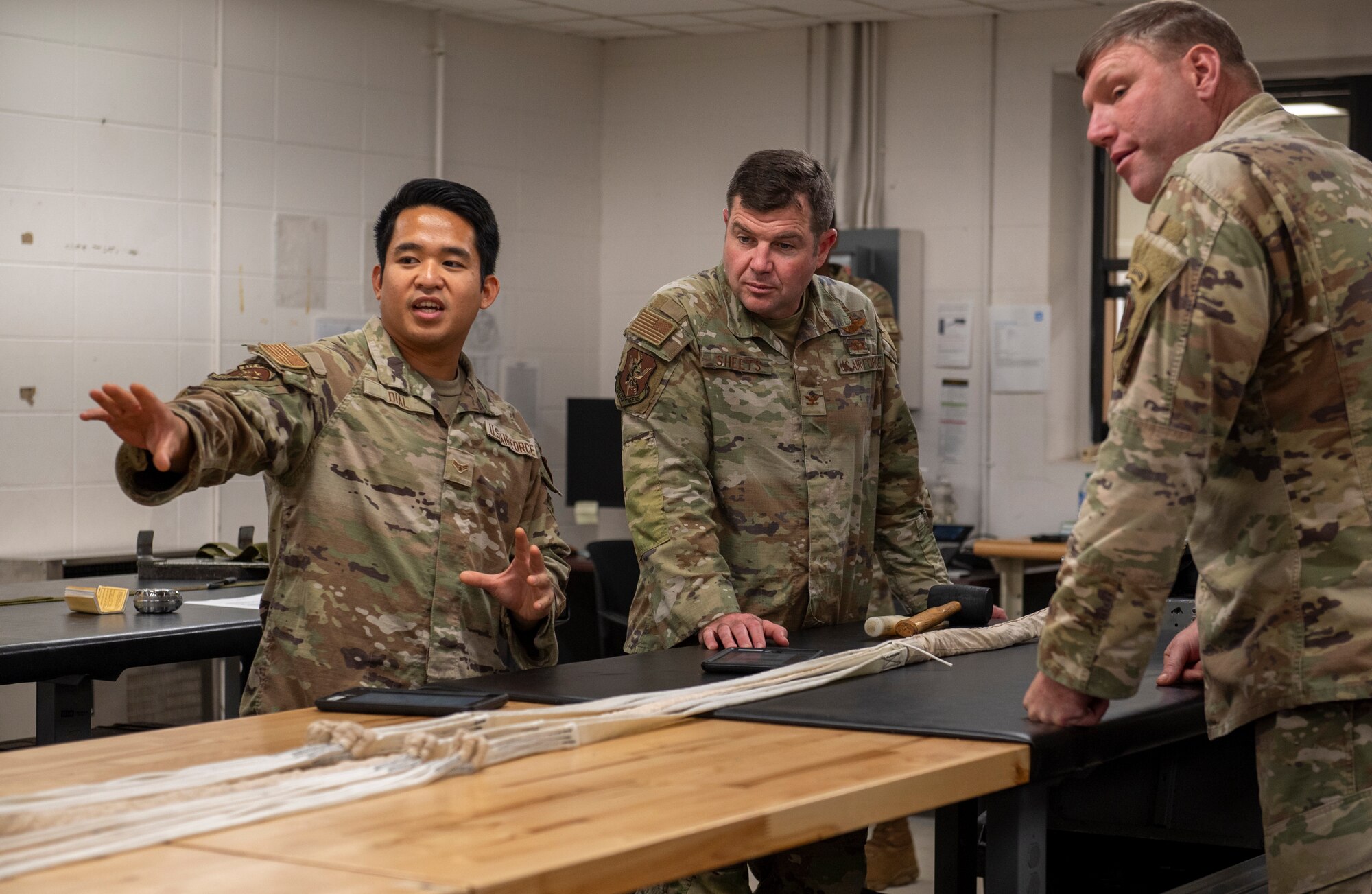 U.S. Air Force Airman 1st Class Kern Dial, 23rd Operations Support Squadron Aircrew Flight Equipment apprentice, left, presents a parachute to Col. Paul Sheets, 23rd Wing commander, center, and Chief Master Sgt. Justin Geers, 23rd Wing command chief, during a battlefield circulation at Moody Air Force Base, Georgia, Nov. 20, 2023. Battlefield circulations allow the base senior leaders to visit different units to learn about the work the Airmen do and get a true picture of how they operate in their day-to-day duties. (U.S. Air Force photo by Airman 1st Class Leonid Soubbotine)