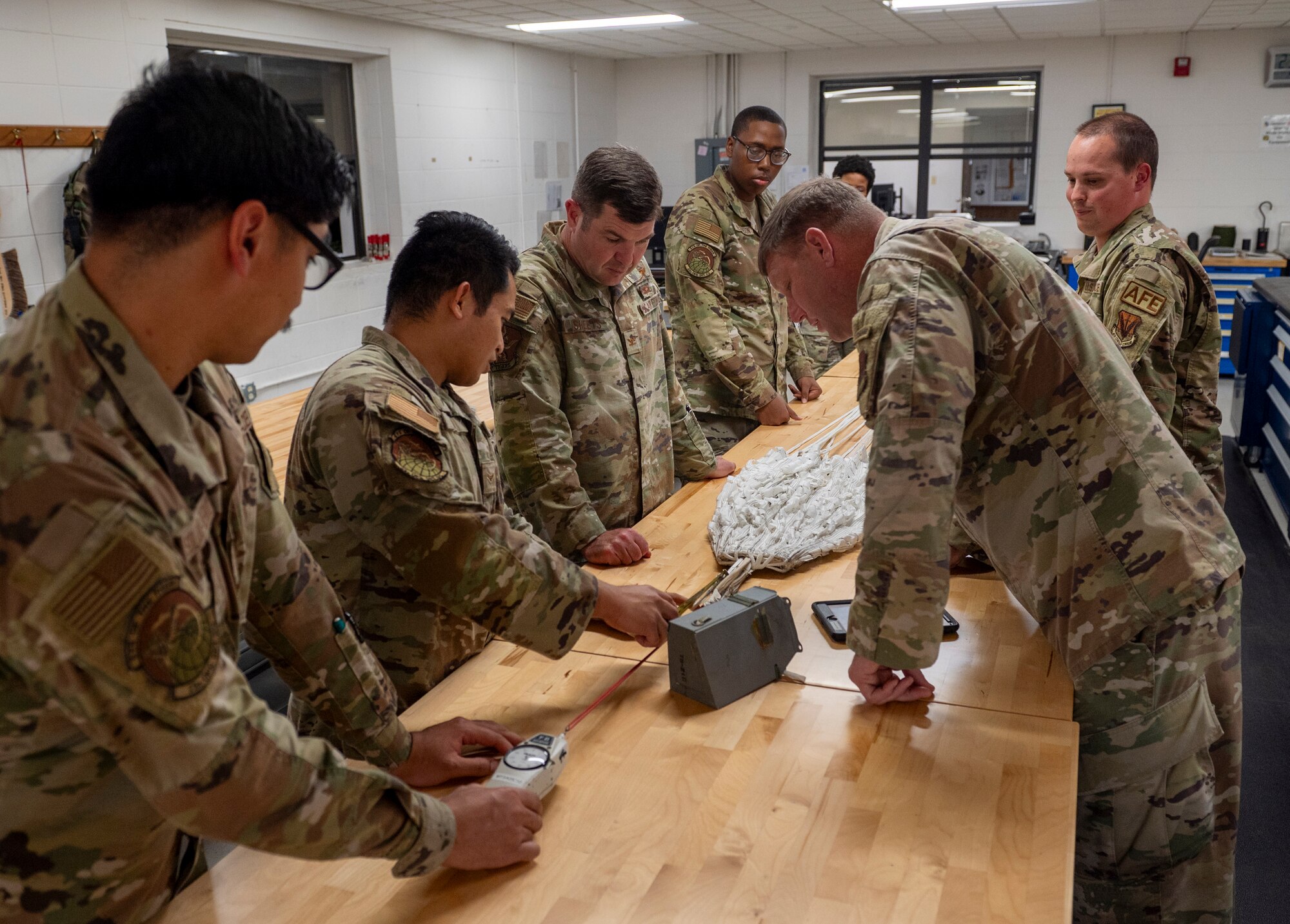 U.S. Air Force Col. Paul Sheets, 23rd Wing commander, left center, and Chief Master Sgt. Justin Geers, 23rd Wing command chief, right, learn about parachutes from a 23rd Operations Support Squadron Aircrew Flight Equipment Airmen, at Moody Air Force Base, Georgia, Nov. 20, 2023. All AFE Airmen ensure function and reliability of flight equipment. (U.S. Air Force photo by Airman 1st Class Leonid Soubbotine)