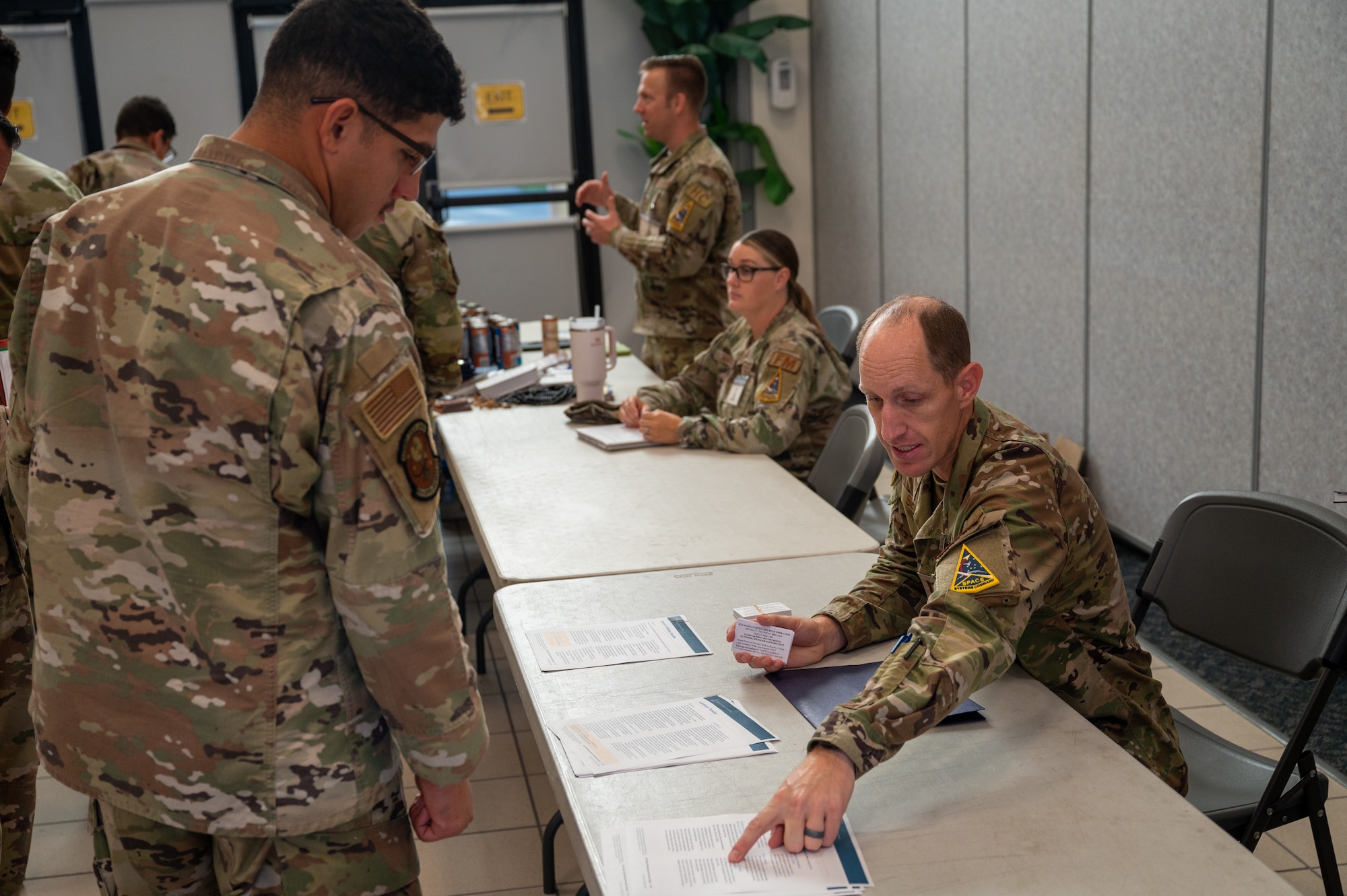 U.S. Air Force Airman 1st Class Jorge Ramos-Alvarado, 45th Civil Engineer Squadron pavement and equipment journeyman (left), and U.S. Air Force Capt. Michael Sevy, Space Launch Delta 45 Legal assistant judge advocate (right), discuss deployment legal aid during a personnel deployment function line at Patrick Space Force Base, Florida, Oct. 5 2023. The 45th Logistics Readiness Squadron hosted its first PDF line, used to help streamline the pre-deployment process for service members, in more than 13 years. (U.S. Space Force photo by Airman 1st Class Spencer Contreras)