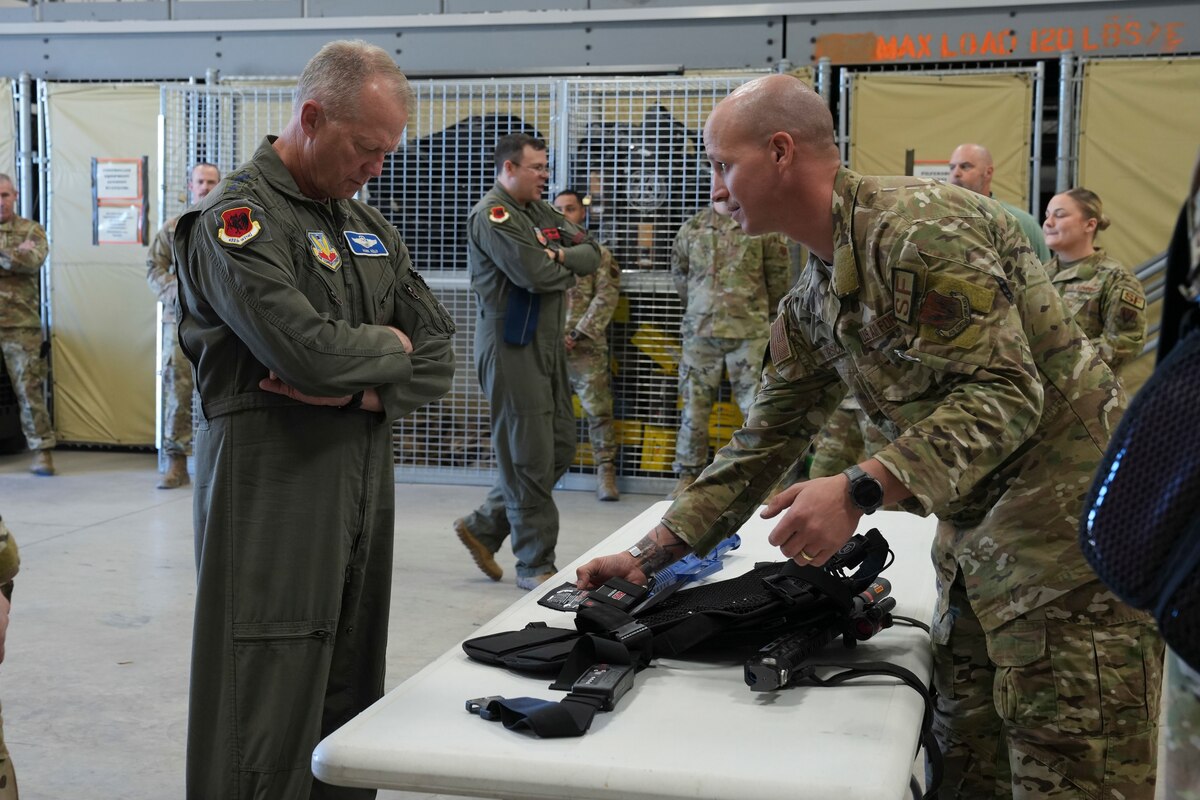U.S. Air Force Gen. Mark Kelly, commander of Air Combat Command looks down at a StressVest while an Airman talks about it.