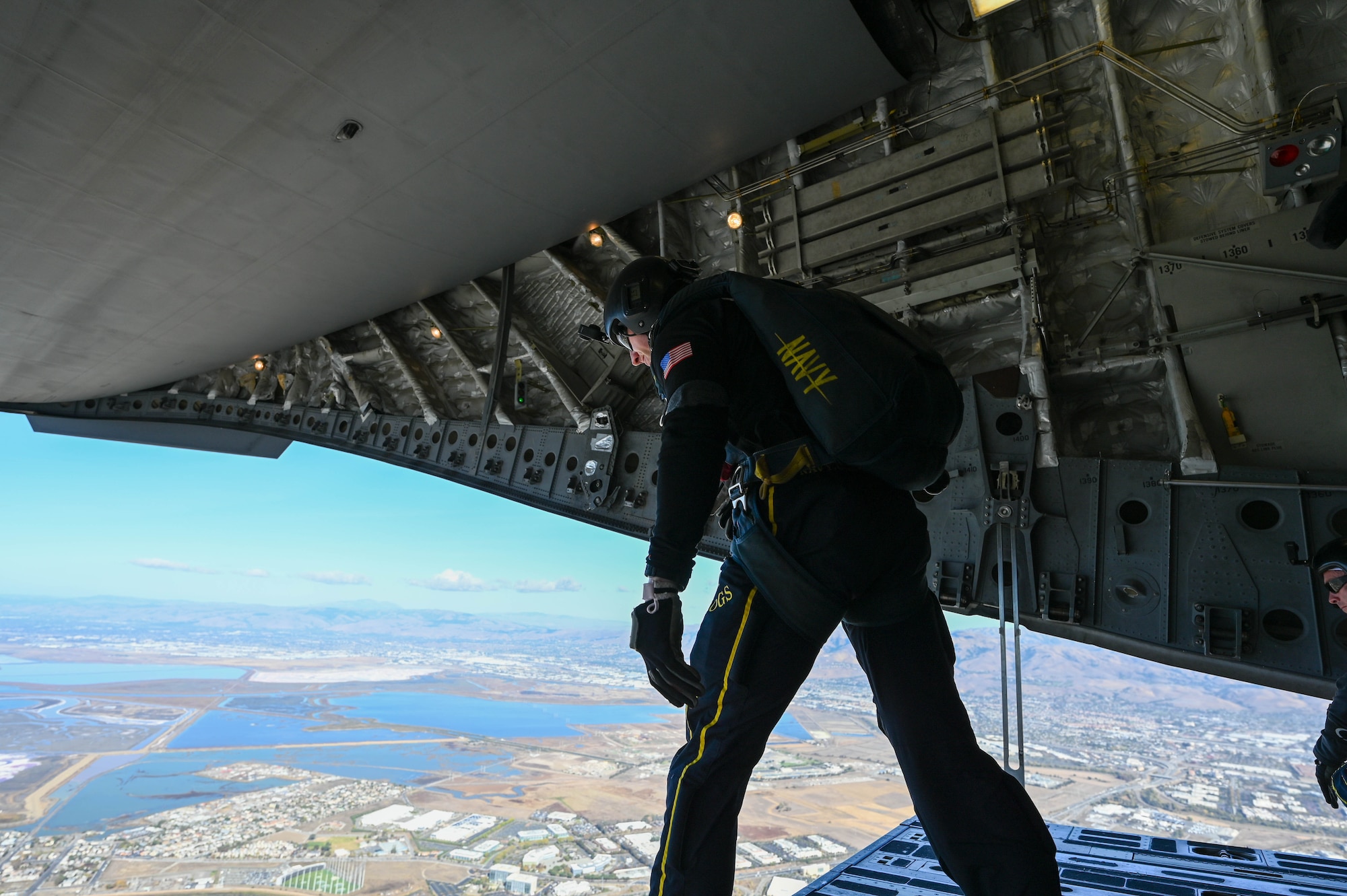 A member of the Navy Parachute Team “The Leap Frogs” waits to drop over Levi’s Stadium in Santa Clara, California, Nov. 19, 2023. The Leap Frogs, commissioned by the Chief of Naval Operations in 1974, are composed of Navy SEALs, Explosive Ordinance Disposal, and other Naval Special Warfare rates. (U.S. Air Force photo by Senior Airman Trenton Jancze)