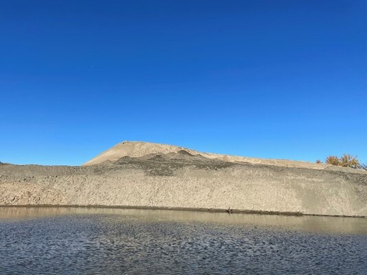 A photo is an island of sand by water.