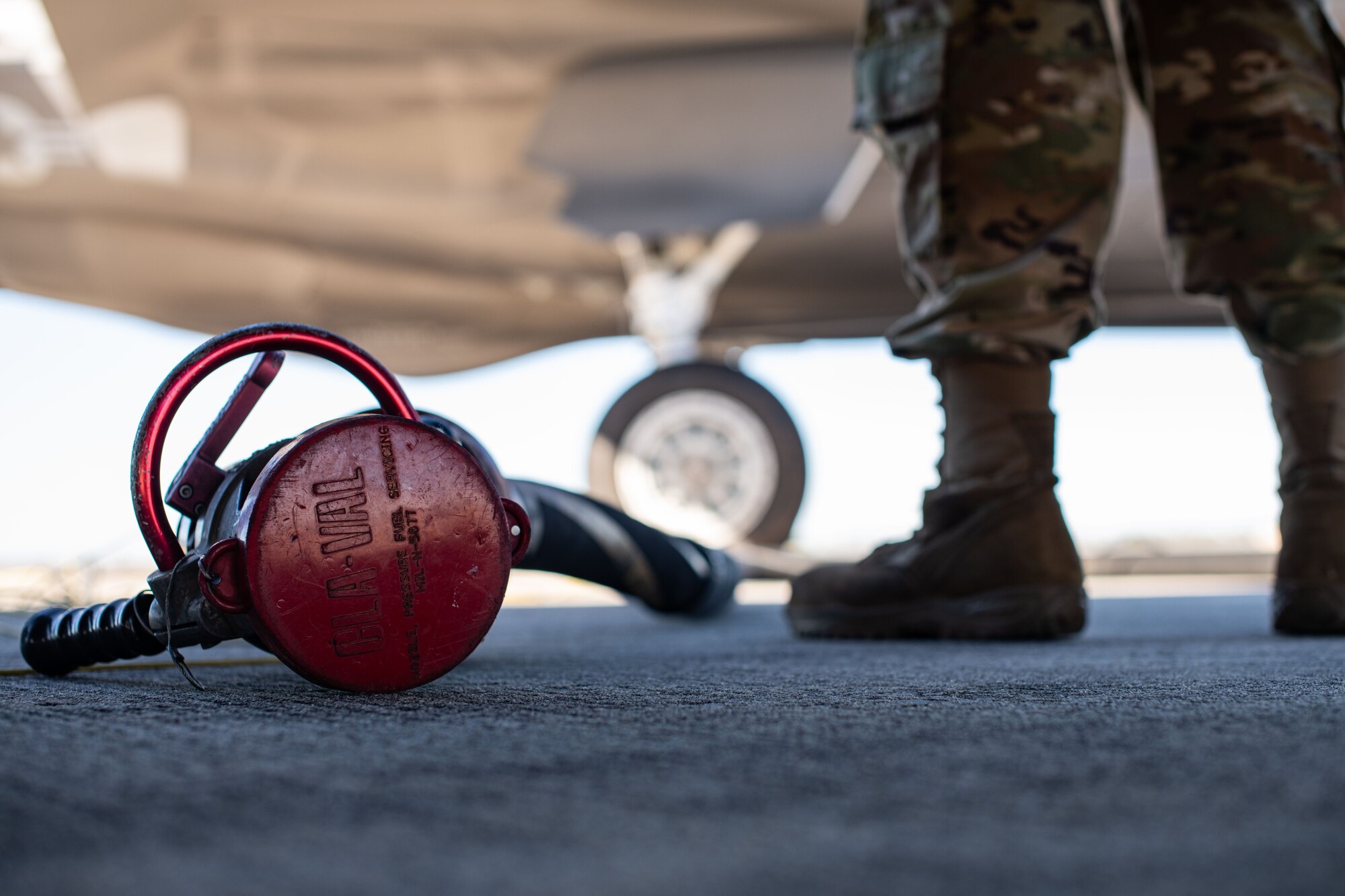 Fuel hose sits on the ground next to an Airman.