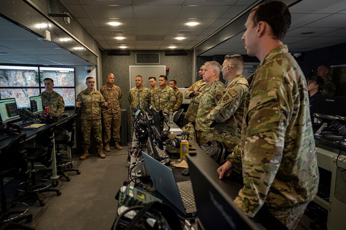 Group of about 20 people stand in operations center