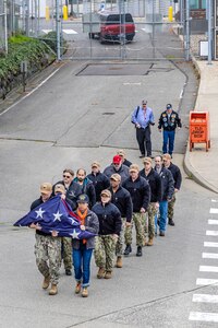 Members of a Puget Sound Naval Shipyard & Intermediate Maintenance Facility color guard carry the old American flag after it was replaced with a new flag Nov. 9, 2023, during a special Veterans Day flag-replacement ceremony near the State Street Gate Entrance at PSNS & IMF in Bremerton, Wash. (U.S. Navy photo by Jeb Fach)