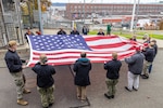 A group of PSNS & IMF Sailors and military veterans prepare to hoist a new American flag near the State Street Gate Entrance at Puget Sound Naval Shipyard & Intermediate Maintenance Facility in Bremerton, Wash. Nov. 9, 2023, during a special Veterans Day flag-replacement ceremony hosted by the Veterans Employee Resource Group. (U.S. Navy photo by Ben Hutto)