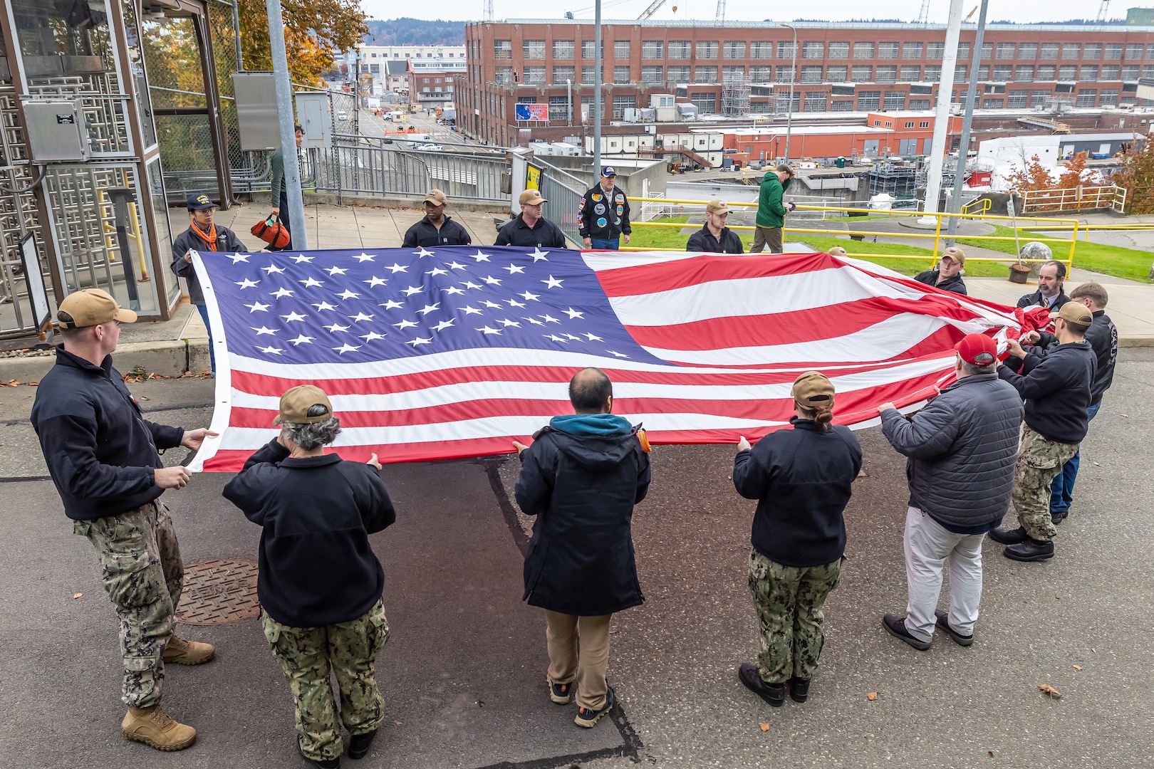 A group of PSNS & IMF Sailors and military veterans prepare to hoist a new American flag near the State Street Gate Entrance at Puget Sound Naval Shipyard & Intermediate Maintenance Facility in Bremerton, Wash. Nov. 9, 2023, during a special Veterans Day flag-replacement ceremony hosted by the Veterans Employee Resource Group. (U.S. Navy photo by Ben Hutto)