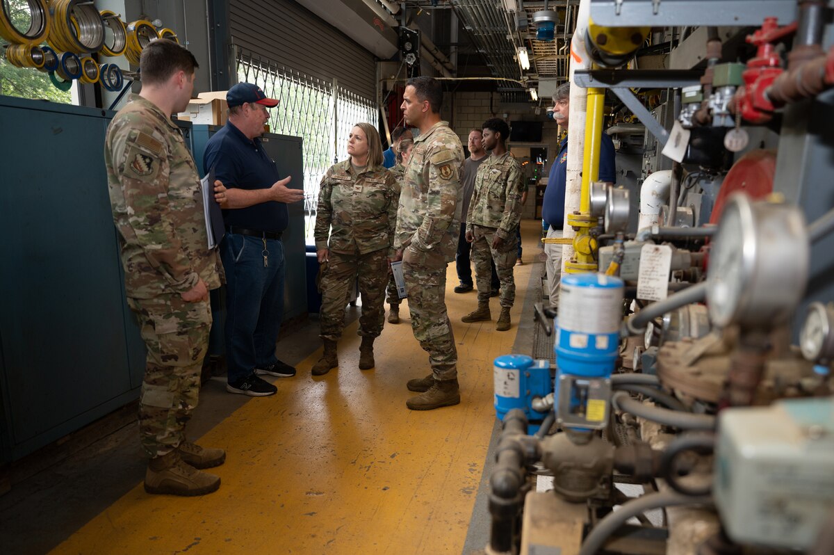 Image of man talking to Airmen during tour of installation steam plant.