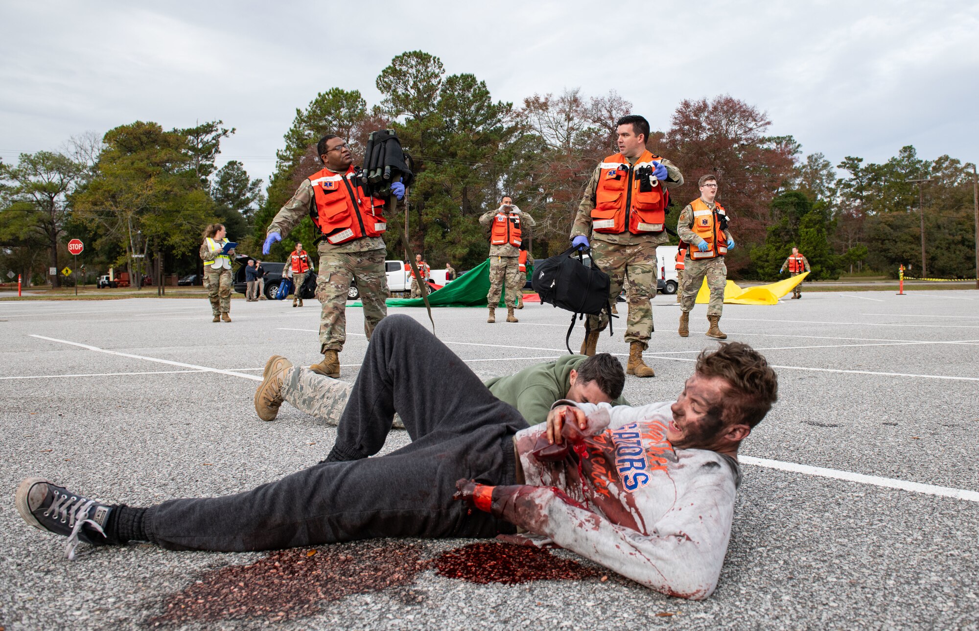 Joint Base Charleston Airmen participate in a medical exercise where they act as patients with simulated wounds. Medical Group staff wear protective hear as they treat the simulated patients.