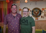 Two men pose for photo with Camp Lemonnier sign and Thanksgiving decor in background.