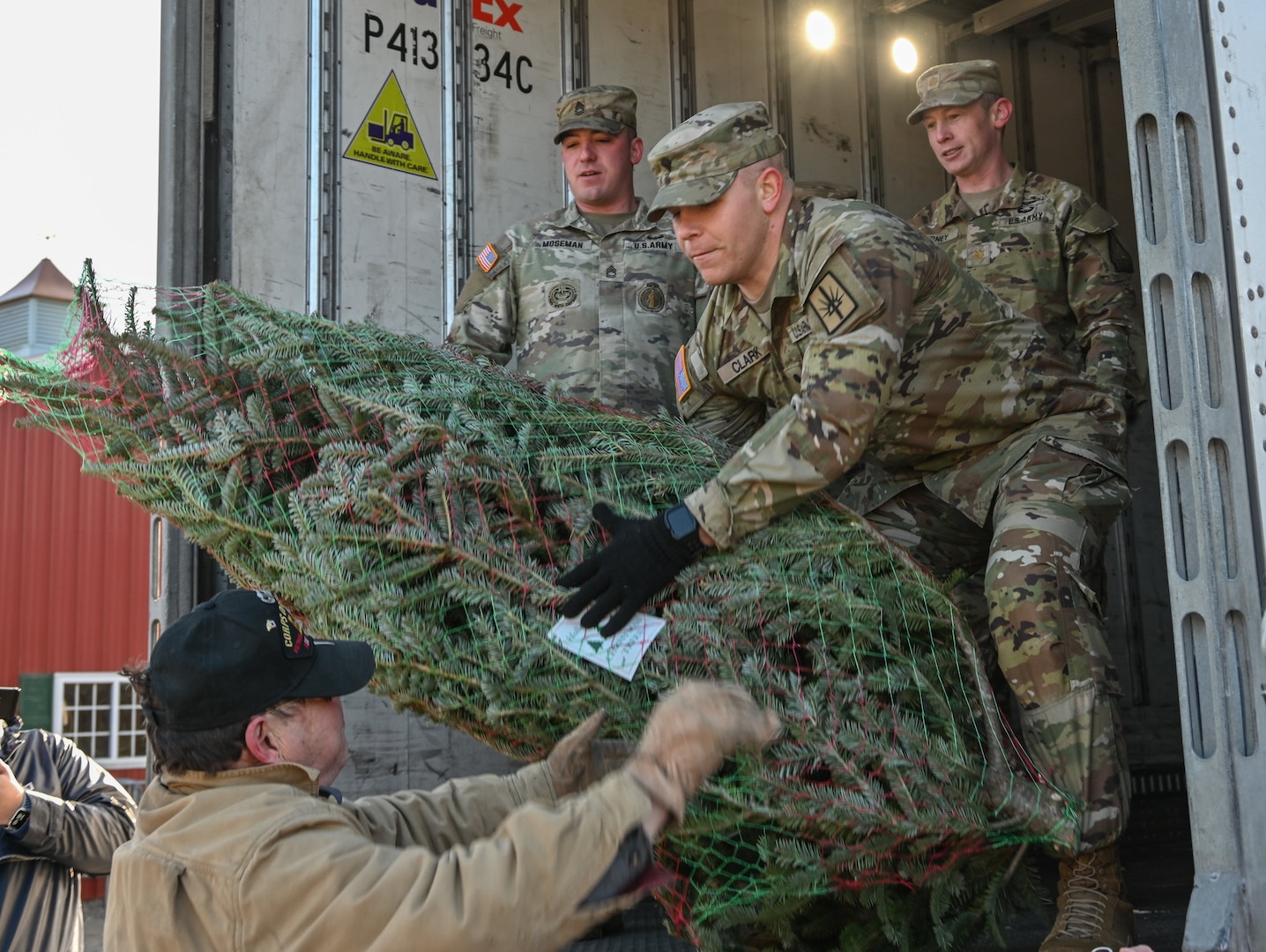 Volunteers pass a tree to New York Army National Guard Spc. Matthew Clark, a recruiting assistant assigned to the 466th Area Support Medical Company, onto a FedEx truck during the annual Trees for Troops event in Ballston Spa, New York, Nov. 28, 2023. The event has been hosted at Ellms Tree Farm for 19 years.