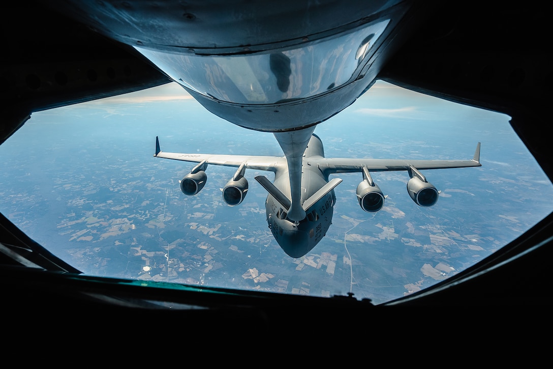 A military refueling aircraft delivers fuel to another aircraft in flight during daylight.
