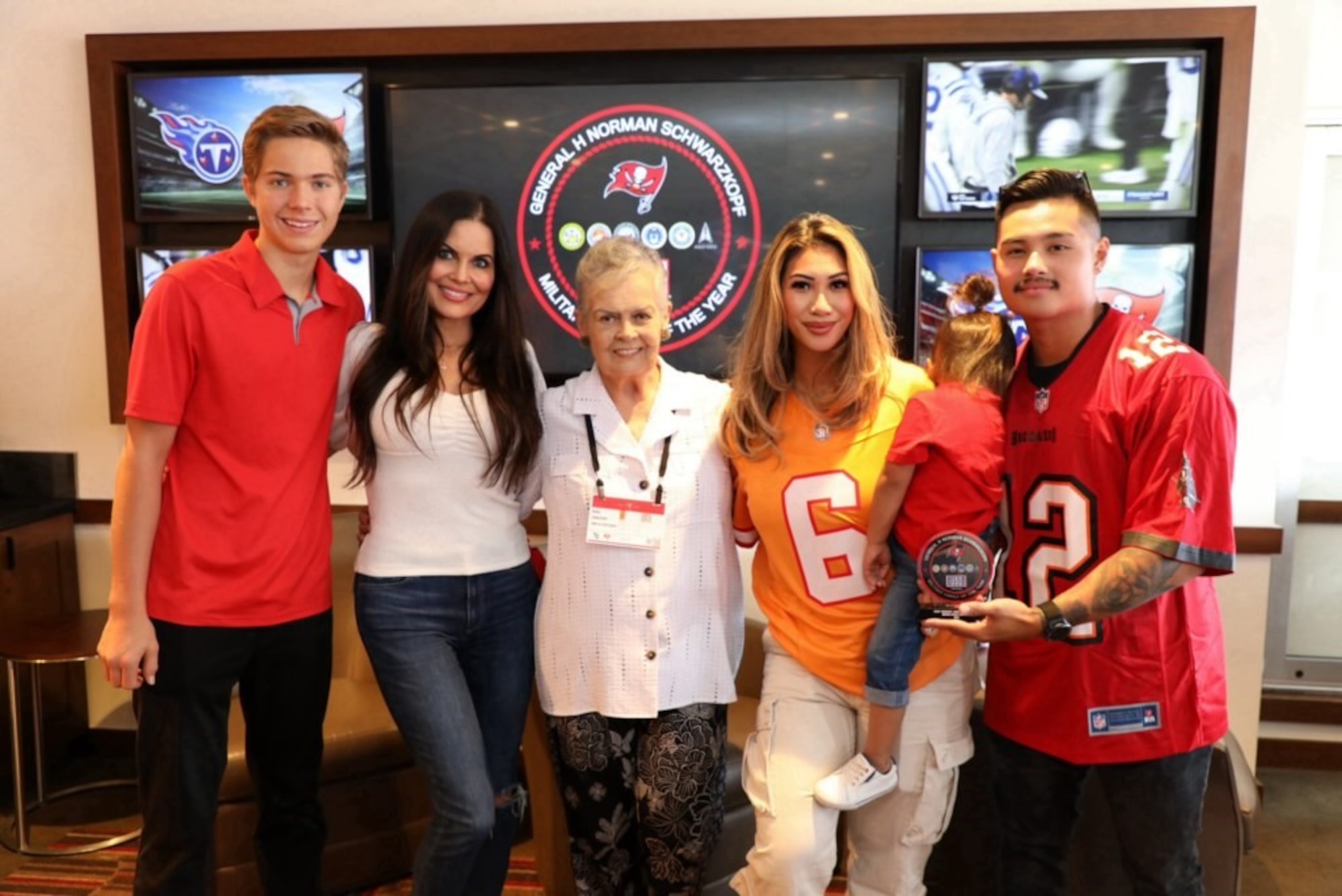 U.S. Air Force Staff Sgt. Jonne Cadua and his family pose with the families of U.S. Space Force Capt. Tiffany Crick and late U.S. Army Gen. Norman Schwarzkop in the Salute to Service Suite at Raymond James Stadium in Tampa, Florida.