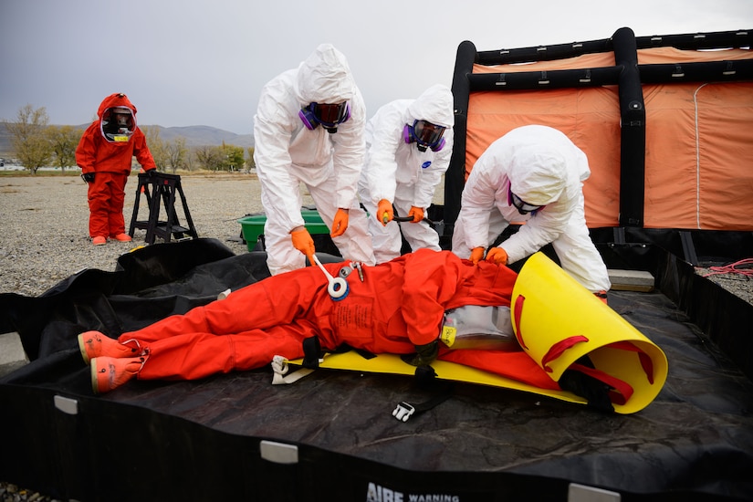 People in hazmat suits decontaminate a simulated casualty during an exercise.