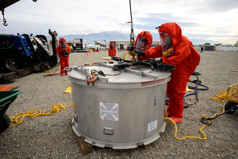 People in hazmat suits work to recover a missile guidance system.