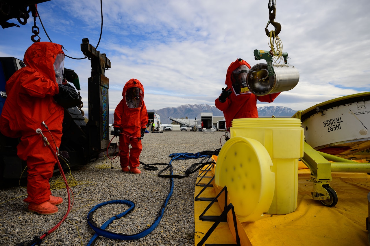 People in hazmat suits work to recover a missile guidance system.